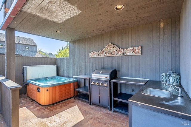 view of patio featuring fence, area for grilling, a sink, and a hot tub