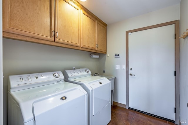 clothes washing area with baseboards, separate washer and dryer, cabinet space, and dark tile patterned flooring