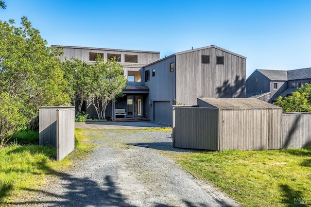 modern home featuring gravel driveway, a shed, and an outbuilding