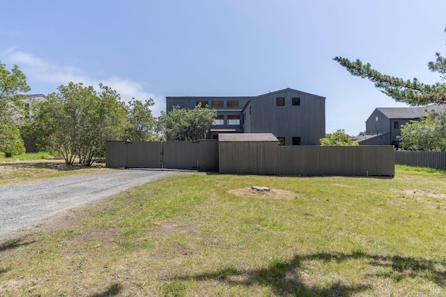 view of yard with gravel driveway, a gate, and fence