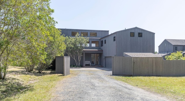 view of front of property with a garage, fence, and gravel driveway