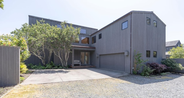 view of front of property featuring driveway, fence, and a garage