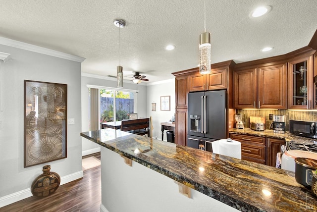 kitchen featuring brown cabinets, a textured ceiling, black microwave, glass insert cabinets, and high end refrigerator