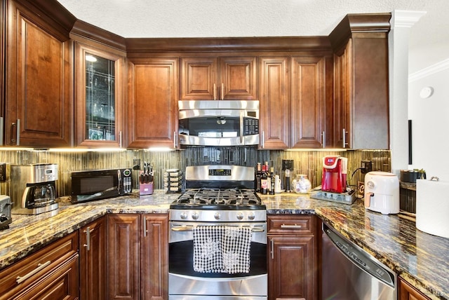 kitchen with decorative backsplash, dark stone countertops, glass insert cabinets, and appliances with stainless steel finishes