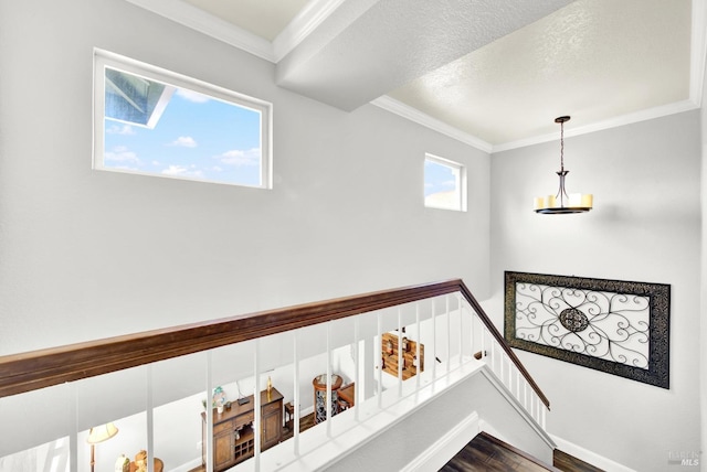 stairs featuring crown molding, a textured ceiling, baseboards, and wood finished floors