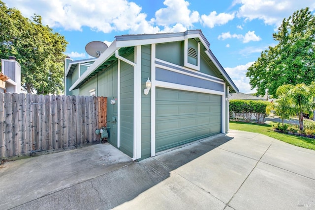 garage featuring concrete driveway and fence