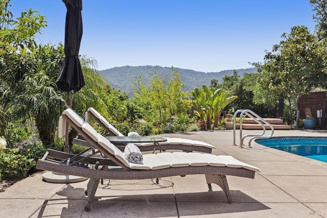 outdoor pool with a mountain view and a patio