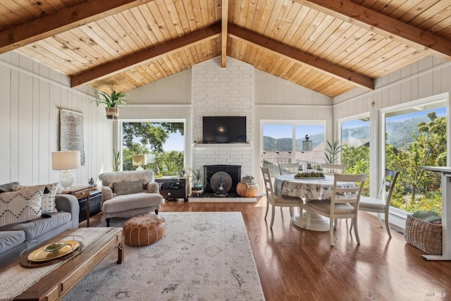 living area with beam ceiling, wood finished floors, a fireplace, and wood ceiling