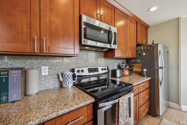kitchen with appliances with stainless steel finishes, brown cabinetry, and tasteful backsplash