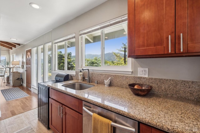 kitchen featuring dishwasher, a sink, light stone counters, and a healthy amount of sunlight