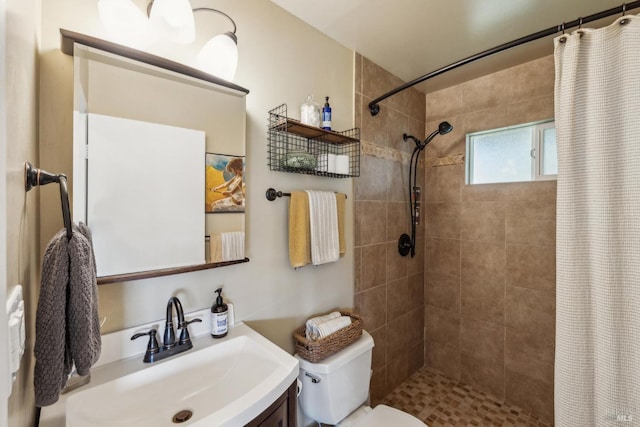 full bathroom featuring toilet, a tile shower, and vanity