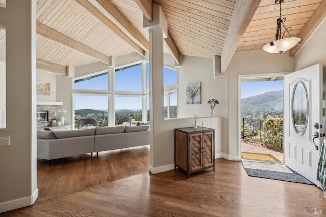 entrance foyer featuring baseboards, wooden ceiling, lofted ceiling with beams, and a mountain view