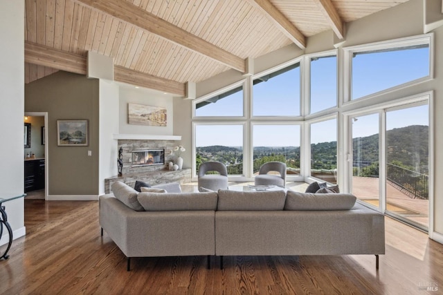 living area with high vaulted ceiling, a stone fireplace, beam ceiling, and a healthy amount of sunlight