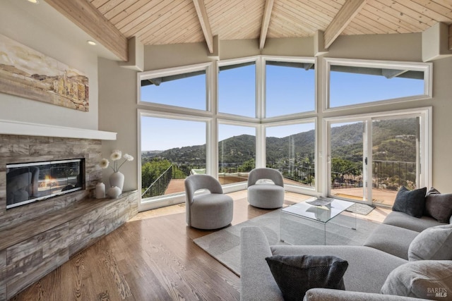 living room with wooden ceiling, a mountain view, a fireplace, beam ceiling, and high vaulted ceiling