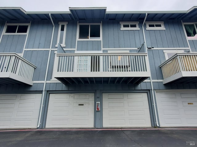 rear view of house featuring a garage and a balcony