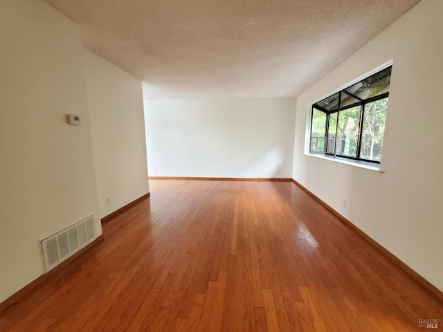 empty room featuring visible vents, light wood finished floors, and baseboards