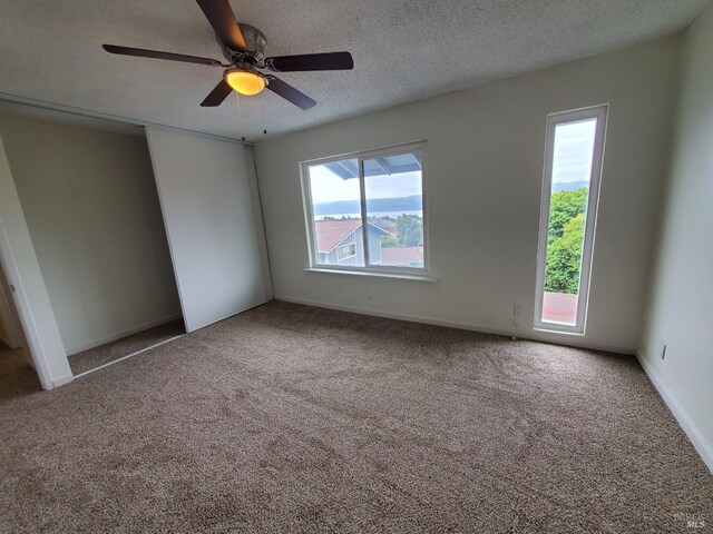 unfurnished bedroom featuring baseboards, a ceiling fan, a textured ceiling, and carpet flooring