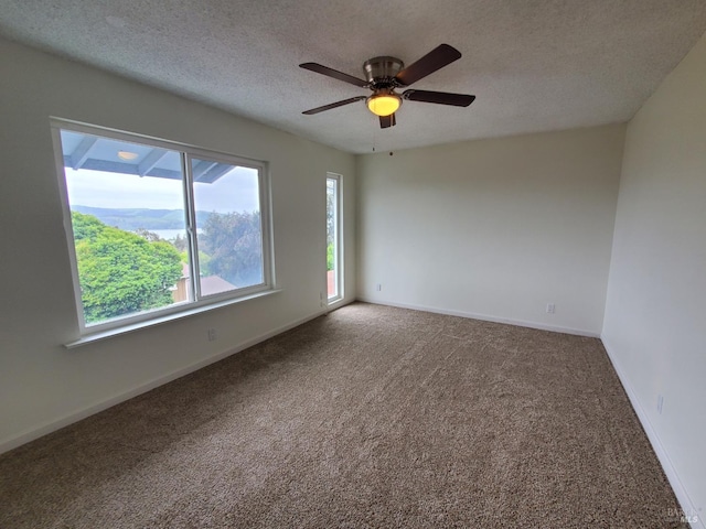 carpeted empty room with a textured ceiling, ceiling fan, and baseboards