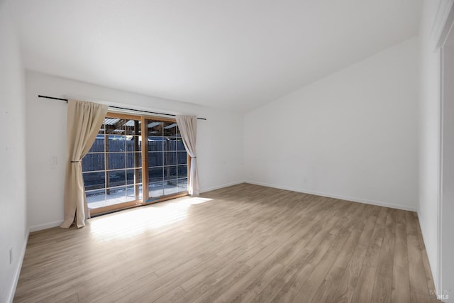 spare room with baseboards and wood finished floors