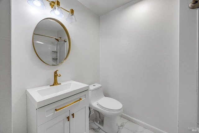 bathroom with vanity, toilet, marble finish floor, and baseboards