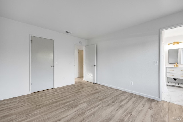 unfurnished bedroom with baseboards, visible vents, ensuite bath, and light wood-style flooring
