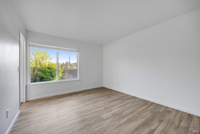 empty room with baseboards and light wood-type flooring