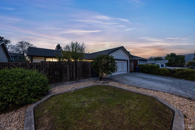 view of front facade featuring driveway, fence, a front lawn, and a garage