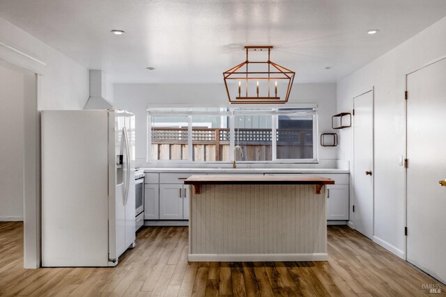kitchen featuring light wood-style flooring, white refrigerator with ice dispenser, a kitchen island, light countertops, and recessed lighting