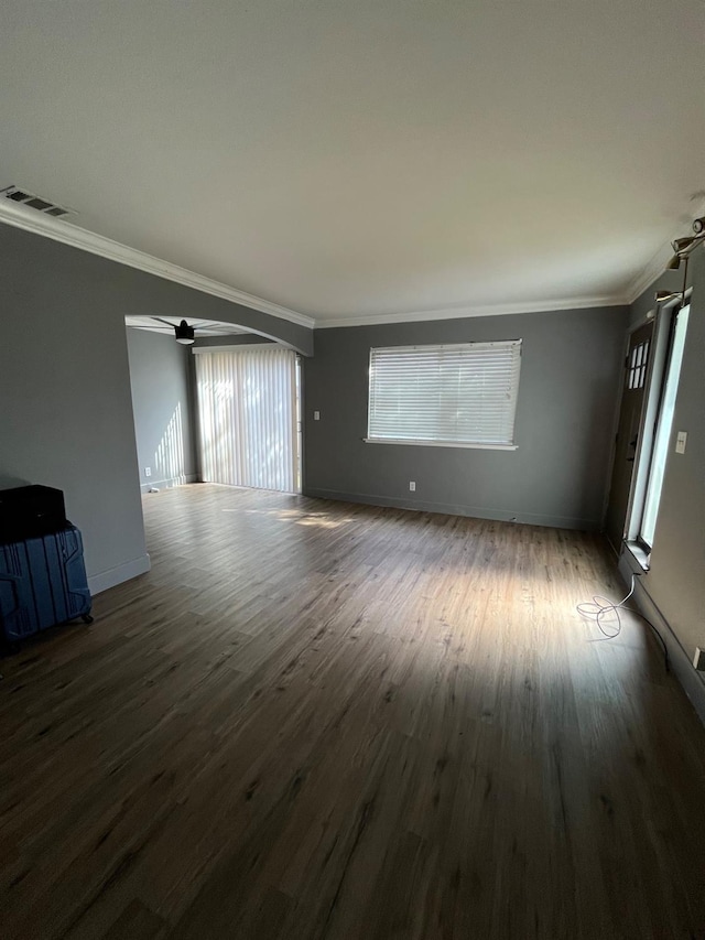 unfurnished living room featuring crown molding, visible vents, baseboards, wood finished floors, and a ceiling fan