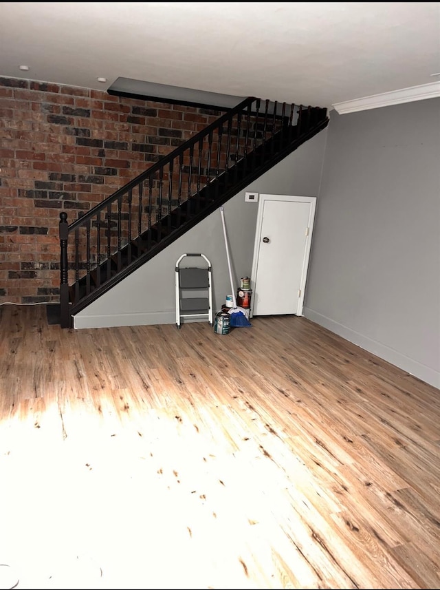unfurnished living room with baseboards, wood finished floors, stairs, and ornamental molding