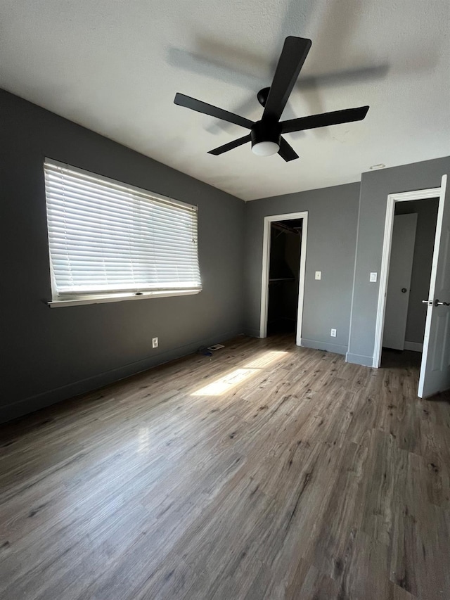 unfurnished bedroom with a closet, ceiling fan, wood finished floors, and baseboards