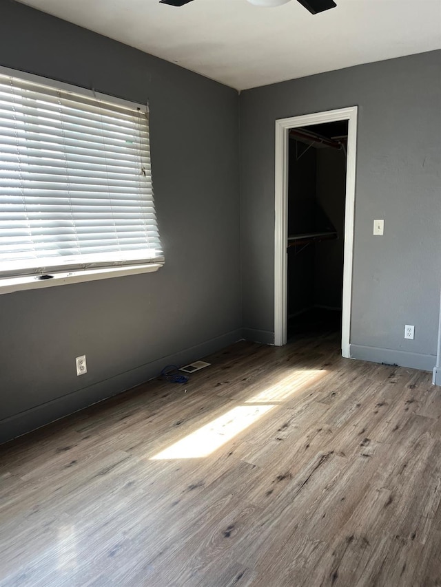 unfurnished bedroom with a closet, visible vents, wood finished floors, and baseboards