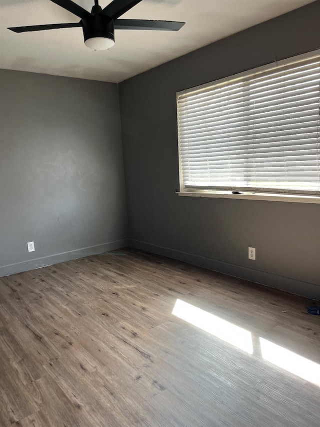 unfurnished room featuring ceiling fan, wood finished floors, and baseboards