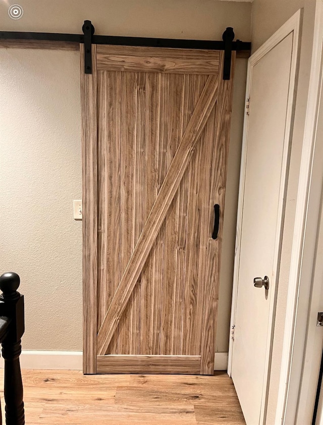 details with wood finished floors, a barn door, and baseboards