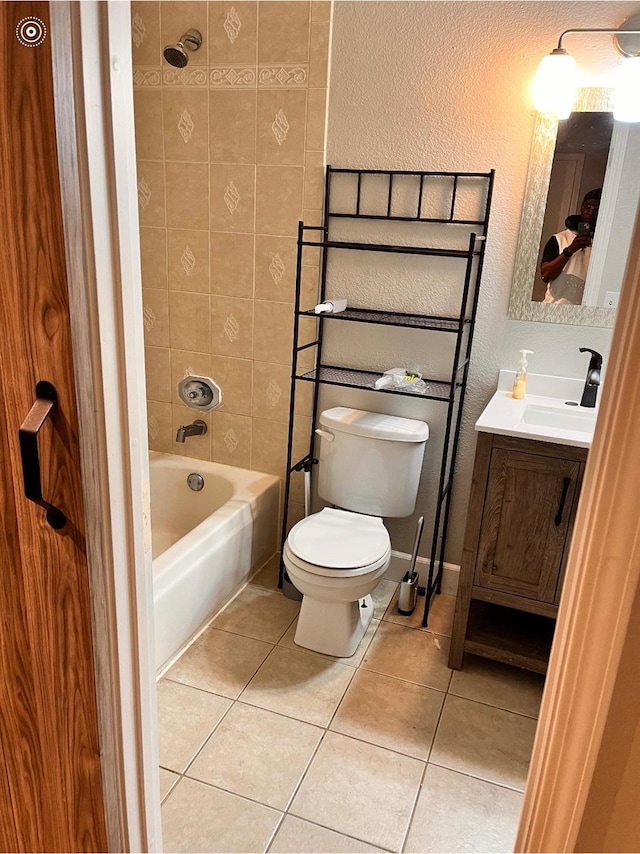 bathroom featuring tile patterned flooring, bathtub / shower combination, toilet, a textured wall, and vanity