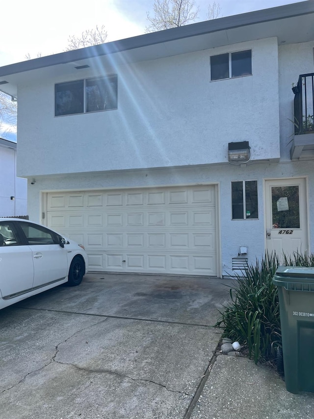 view of side of property with stucco siding, driveway, and a garage