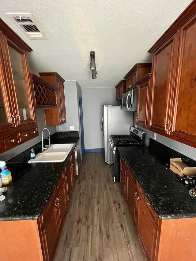 kitchen with a sink, visible vents, stainless steel appliances, baseboards, and light wood finished floors