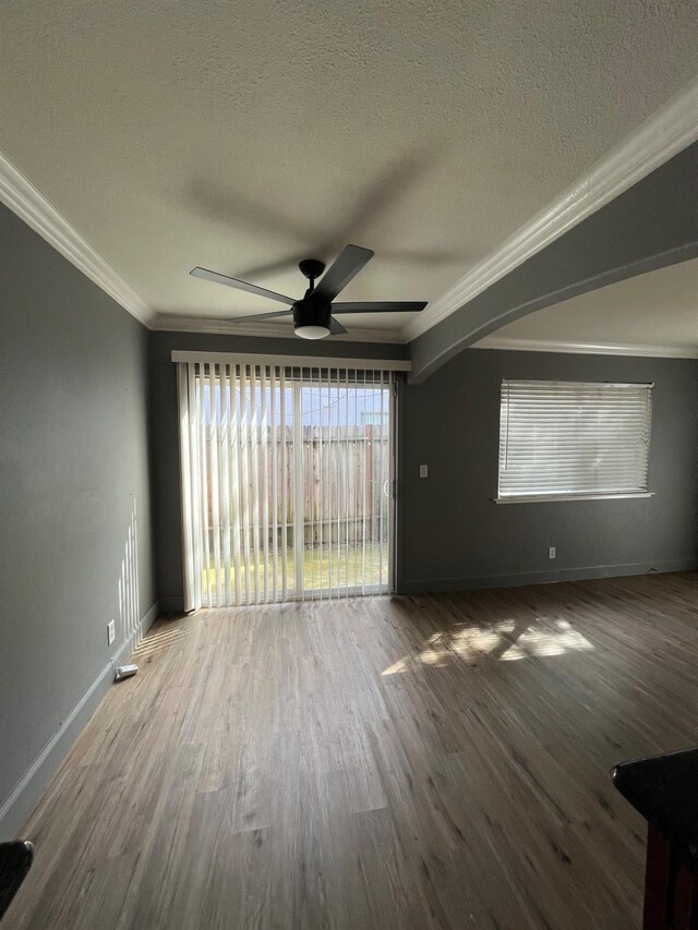 unfurnished living room with a textured ceiling, wood finished floors, a ceiling fan, and ornamental molding
