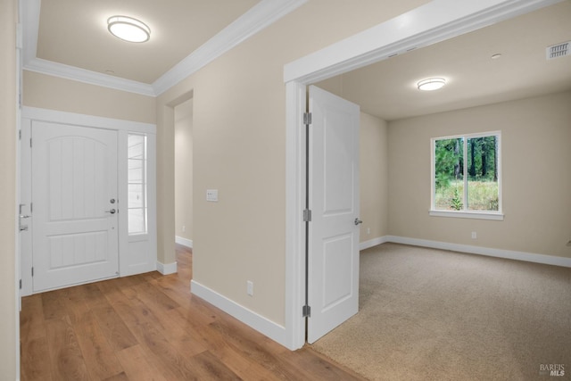 entryway featuring light wood-style floors, crown molding, visible vents, and baseboards