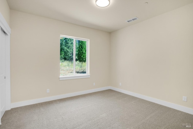 carpeted empty room with visible vents and baseboards