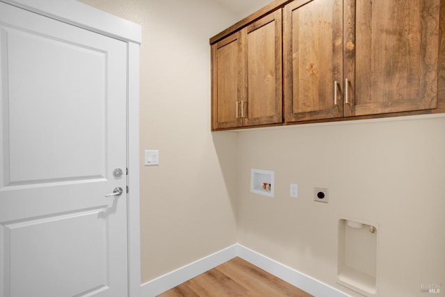 clothes washing area with hookup for a washing machine, electric dryer hookup, cabinet space, light wood finished floors, and baseboards