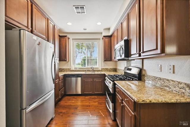 kitchen featuring recessed lighting, a sink, dark wood-style flooring, light stone counters, and appliances with stainless steel finishes