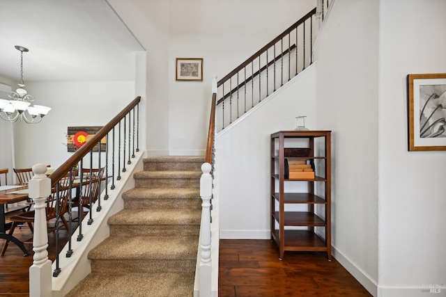 stairs featuring wood finished floors, a chandelier, and baseboards