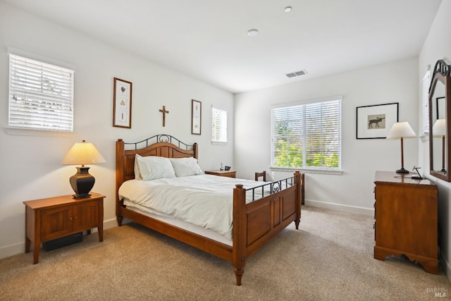 bedroom featuring baseboards, visible vents, and light carpet