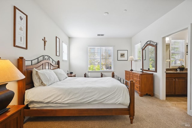 bedroom featuring light colored carpet, visible vents, and ensuite bathroom