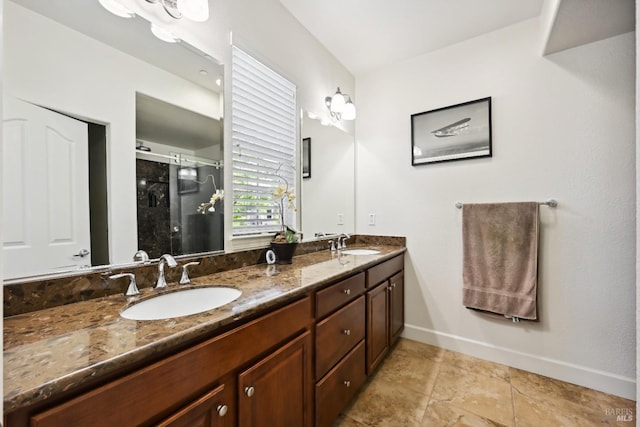 full bath with double vanity, baseboards, a stall shower, and a sink