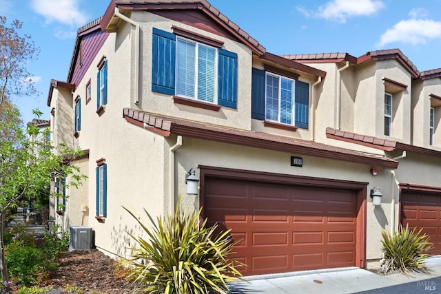 view of front of home featuring stucco siding, a tile roof, and a garage