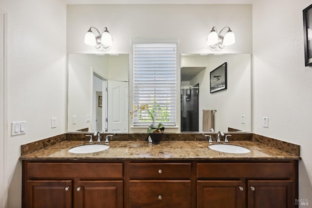 full bathroom with a stall shower, double vanity, and a sink