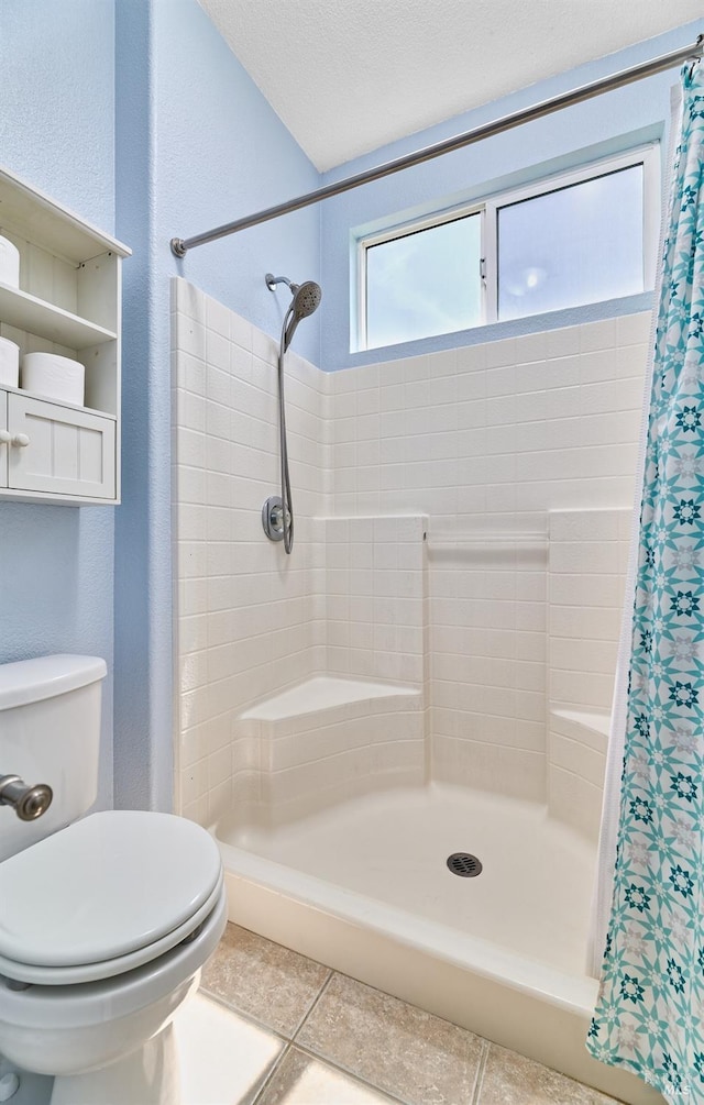 bathroom with a shower stall, toilet, and tile patterned flooring