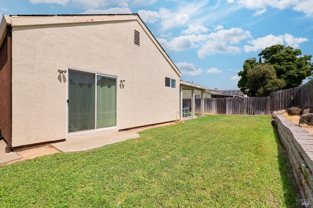 back of house with stucco siding, a yard, and a fenced backyard